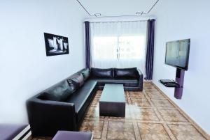 a living room with a black leather couch and a tv at Appart Clim Wifi 700m de la Plage in Saïdia