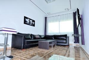 a living room with a black leather couch and a window at Appart Clim Wifi 700m de la Plage in Saïdia
