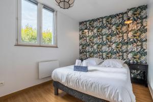 una camera da letto con un letto grande con carta da parati floreale di Le Cottage du Louvre a Lens