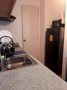a kitchen counter with a sink and a refrigerator at Arezzo Place Davao - Condo Rentals WITH FREE POOL, 200MBPS CONNECTION in Lanang