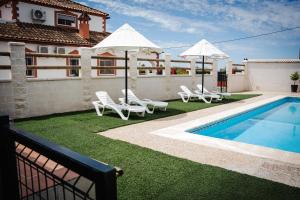 ein Pool mit Stühlen und Sonnenschirmen neben einem Haus in der Unterkunft Casa Martina in La Carlota