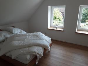 a white bedroom with a bed and two windows at Monteurwohnung - Ferienwohnung in Piesberger