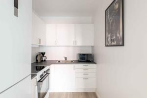 a white kitchen with white cabinets and a sink at Lovely City Apartments in Vibrant Area of Copenhagen in Copenhagen +133 photos