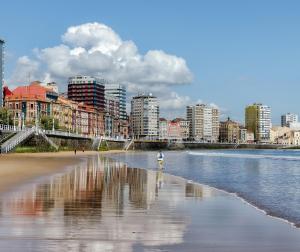 a person standing on a beach with a city in the background at La Buhardilla de la Escalerona - 2 Hab - VUT-4354-AS in Gijón