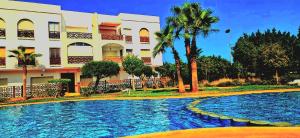 a swimming pool in front of a building at Résidence Yasmine Saïdia in Saïdia