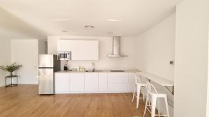 a kitchen with white cabinets and a stainless steel refrigerator at Moderno y lujoso apartamento CASTELAR in Alcázar de San Juan