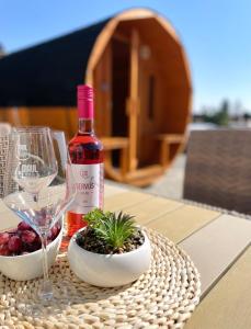 a bottle of wine and a bowl of fruit and a glass at Lator Apartmanház in Villány +25 photos
