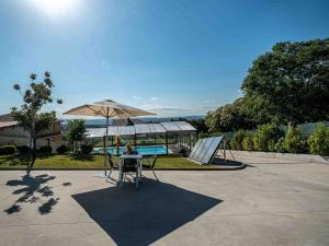 a table and an umbrella next to a pool at Lujo a estrenar con piscina cubierta in Teo