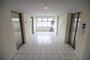 an empty hallway of an office building with doors and a tile floor at ARBA Dramaga Tower by Rendirooms in Bogor