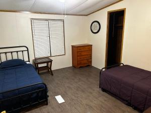a bedroom with two beds and a dresser and a clock at Woolen Lake House in Columbia