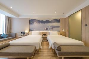 a hotel room with two beds and a painting on the wall at Atour Hotel Hangzhou Binjiang Jiangling Road in Hangzhou