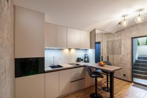 a kitchen with white cabinets and a wooden table at Royal Hot Jucuzzi Apartment in Lviv