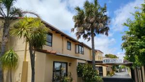 a hotel with palm trees in front of a building at Hobson's Choice Motel in Dargaville