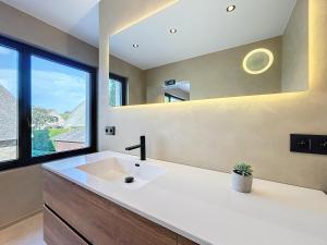 a bathroom with a white sink and a window at Villa Hélène - 2 newly renovated flats for rent together or separately in Koksijde +68 photos