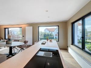 a living room with a table and some windows at Villa Hélène - 2 newly renovated flats for rent together or separately in Koksijde