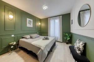 a green bedroom with a bed and a mirror at Appartement moderne & lumineux aux portes de Paris in LʼÎle-Saint-Denis