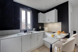 a kitchen with white cabinets and a table with chairs at Appartement moderne & lumineux aux portes de Paris in LʼÎle-Saint-Denis