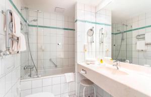 a white bathroom with a sink and a shower at Strandhotel Sylt Westerland in Westerland