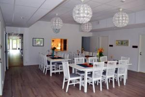 una sala da pranzo con tavoli e sedie bianchi e lampadari di Bedtime a Holmsund