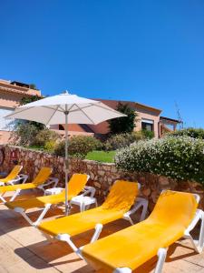 a row of yellow lounge chairs and an umbrella at Apartamentos Turísticos Buganvilia in Lagos