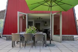 a table and chairs with a green umbrella on a patio at De Pan in Hapert