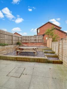 a wooden picnic table in front of a fence at Amaya Three - Newly Renovated - Sleeps 6 - Grantham - Garden & Driveway - Free Gym Access in Grantham +22 photos