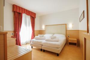 sypialnia z dwoma łóżkami i dużym oknem w obiekcie Club Hotel e Residence La Vela w orbole