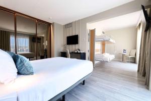 a hotel room with a large white bed and a living room at TRYP by Wyndham Lisboa Caparica Mar in Costa da Caparica