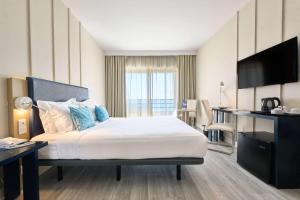 a hotel room with a bed and a flat screen tv at TRYP by Wyndham Lisboa Caparica Mar in Costa da Caparica