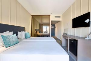 a hotel room with two beds and a flat screen tv at TRYP by Wyndham Lisboa Caparica Mar in Costa da Caparica
