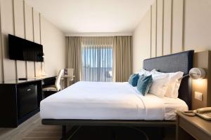 a hotel room with a large bed and a desk at TRYP by Wyndham Lisboa Caparica Mar in Costa da Caparica
