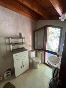 een badkamer met toilet, wastafel en raam bij La Cardosa in Comillas