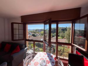 een woonkamer met een tafel en een aantal ramen bij La Cardosa in Comillas