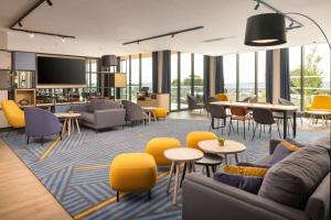 a living room with yellow chairs and tables at Hyatt Place Rouen in Rouen