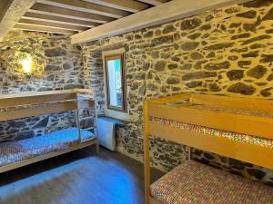 a room with two bunk beds in a stone wall at Chalet confortable à Ascou avec vue sur la montagne in Ascou