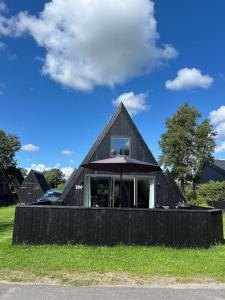 a black house with an umbrella in the grass at Skønt Sommerhus Golfhytte midt i skønne omgivelser in Gatten