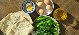 a table with a sandwich and eggs and a bowl of lettuce at Budur Guesthouse in Ijevan +21 photos
