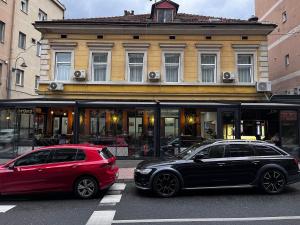 two cars parked on a street in front of a building at Residence Inn Orijent in Sarajevo