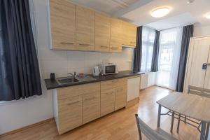 a kitchen with wooden cabinets and a sink and a table at Harangtorony Szálló in Kőszeg