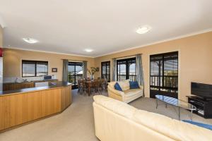 a living room with a couch and a kitchen at Sea Change - Spacious Family Holiday Accommodation Pet friendly in Ledge Point