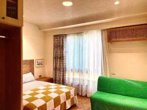 a bedroom with a bed and a window with a green couch at AARU Maadi Luxe Retreat in Cairo