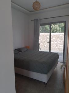 a bedroom with a bed and a large window at Charmante maison indépendante in Oulad el Madani