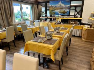 uma sala de jantar com mesas amarelas e cadeiras brancas em Hotel Adonis em Zermatt