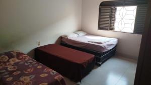 a small room with two beds and a window at Quarto Uberlandia in Uberlândia