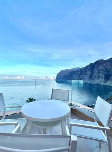 ein weißer Tisch und Stühle auf einem Balkon mit Blick auf das Meer in der Unterkunft Apartamento incleibles vistas al océano y piscina. in Acantilado de los Gigantes