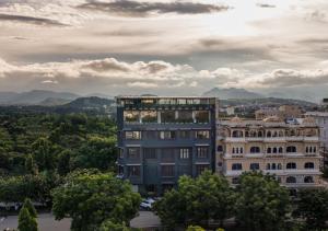 a tall building with trees in front of a city at Kudos-My Downtown Hotel in Udaipur +20 photos