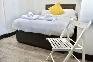 1 cama con toallas y 1 silla en una habitación en The Copperfield Apartment - Broadstairs Central - By Goldex Coastal Breaks, en Broadstairs
