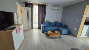 Una sala de estar con un sofá azul y un televisor. en Pomiculturii Residence 9, en Timisoara