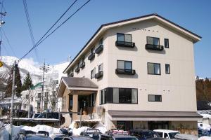 Hakuba Glad Inn Ebisuya في هاكوبا: مبنى كبير فيه سيارات تقف امامه