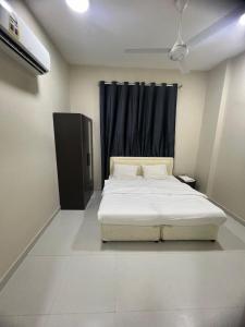 a bedroom with a white bed with a black curtain at RED-6 algarbeia in Salalah +12 photos